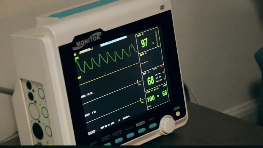 Patient monitor displaying a green waveform and vital signs