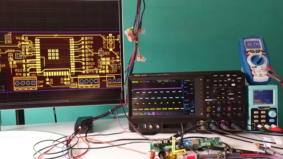 Electronics workbench with oscilloscope, probes and PCB layout monitor