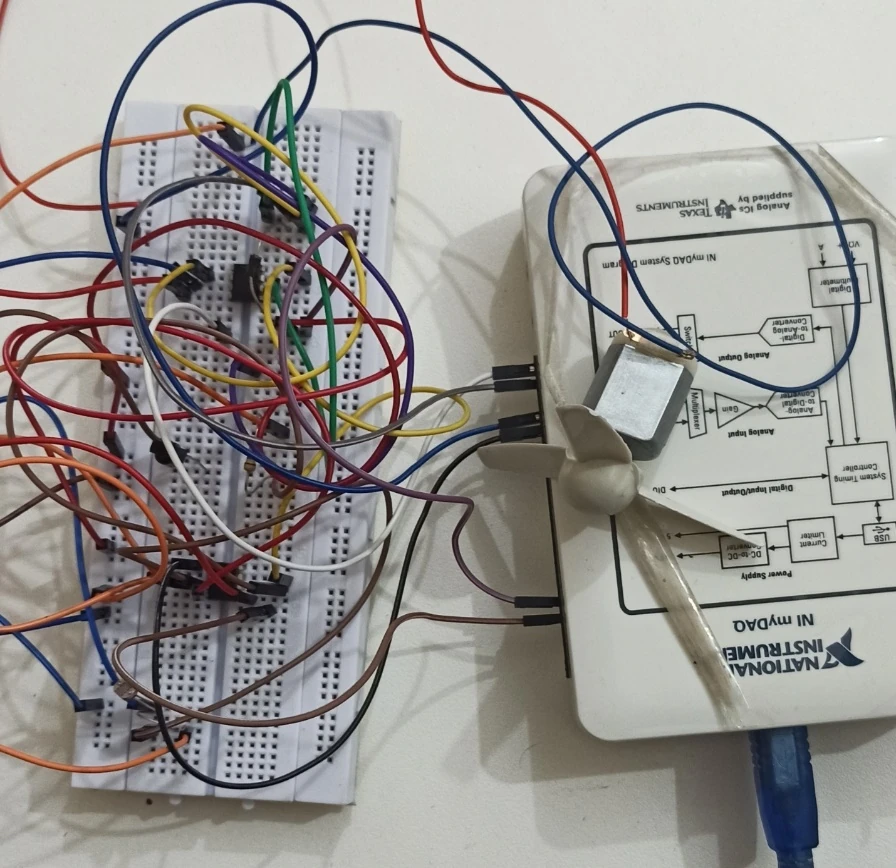 Wired breadboard beside a fan motor and a labeled NI myDAQ data-acquisition device.