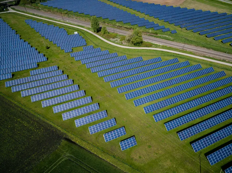 Aerial view of blue solar panel arrays in a green field